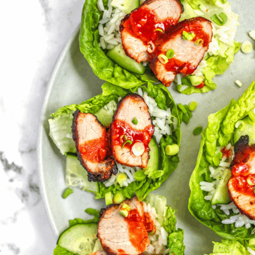 Crispy Korean-style pork served in lettuce leaves with shredded vegetables, sesame seeds, and gochujang sauce