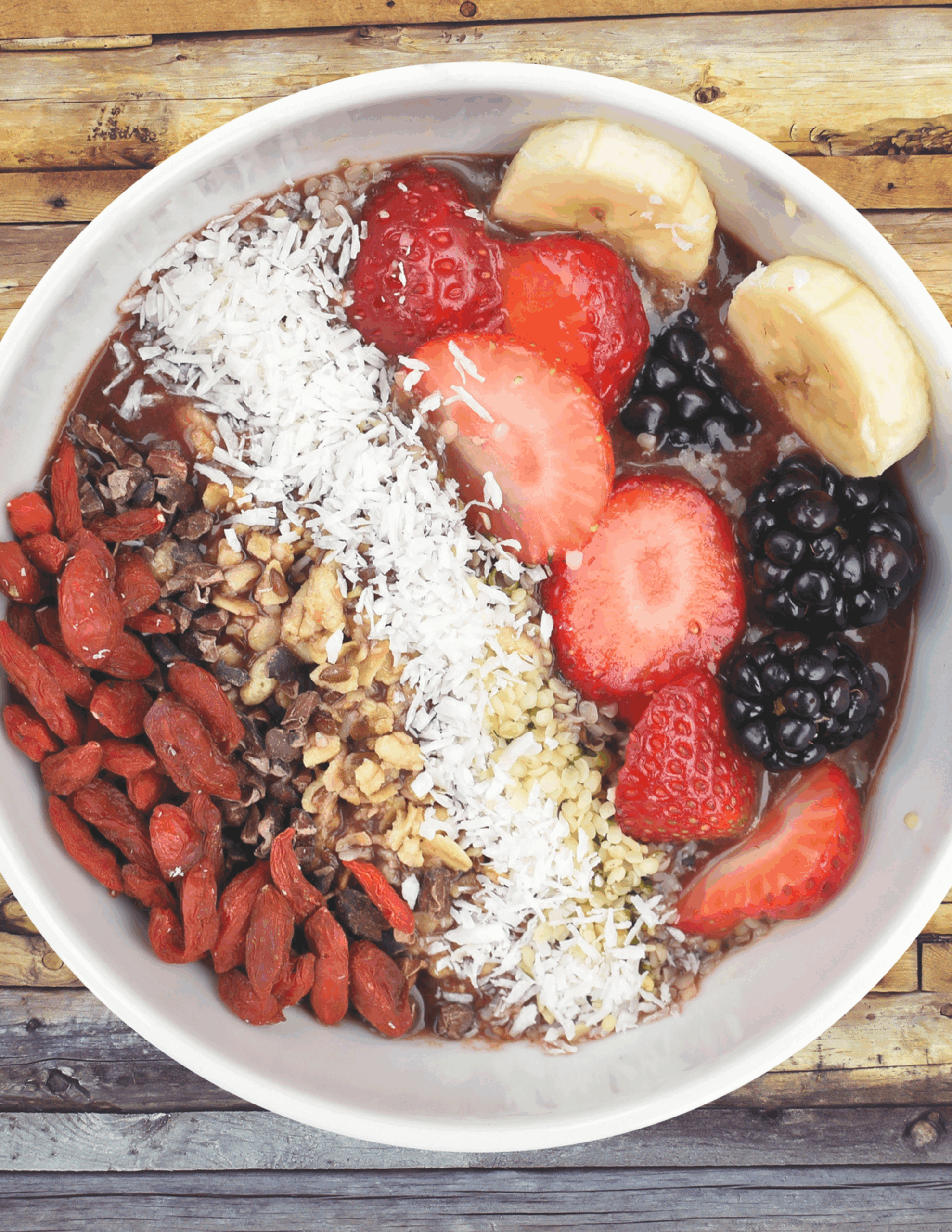 A vibrant acai bowl topped with fresh berries, sliced banana, crunchy granola, chia seeds, and a drizzle of honey, served in a rustic ceramic bowl for a colourful, nutrient-rich breakfast.