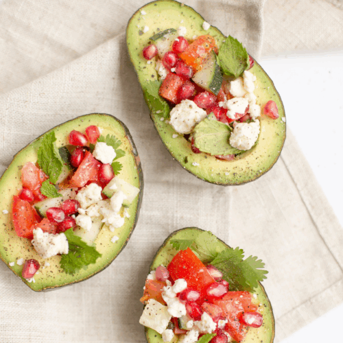 A vibrant plate featuring creamy avocado slices and crumbly feta cheese on crisp wholegrain crackers, garnished with fresh herbs and a drizzle of olive oil for a wholesome, nutrient-rich snack.
