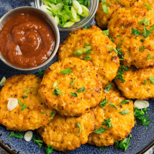 Golden-brown Cauliflower Hash Browns stacked on a plate, crisp on the outside and tender inside, garnished with fresh herbs.