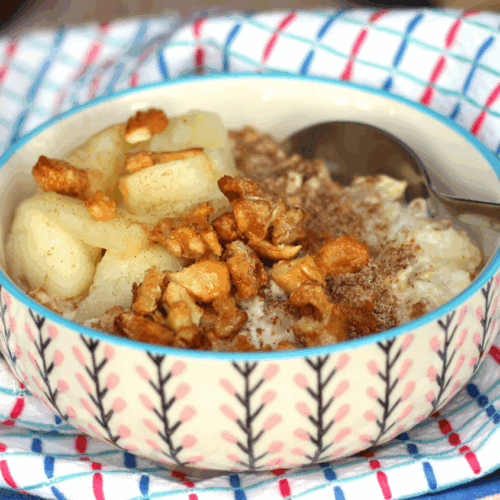 A mason jar filled with creamy apple pie overnight oats, layered with tender cinnamon-spiced apple chunks and sprinkled with a golden oat crumble, garnished with apple slices and a dusting of cinnamon.