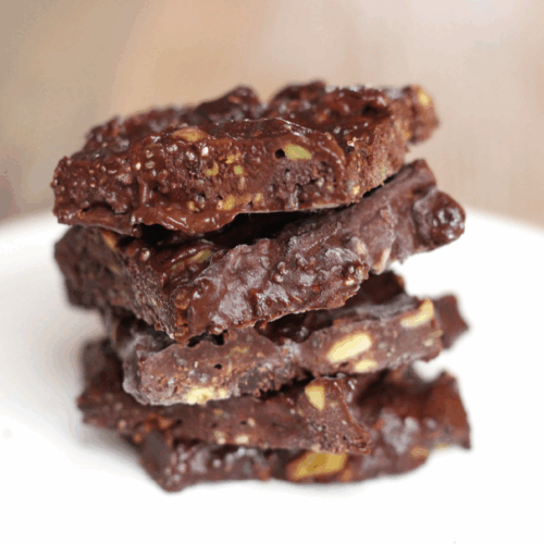 Chocolate avocado protein bites with cocoa powder, oats, and crushed nuts on a parchment sheet