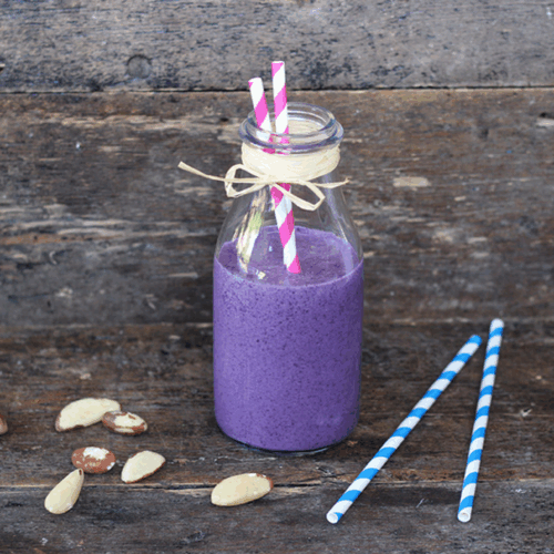 Vibrant smoothie with mixed berries, Brazil nuts, and a creamy swirl in a clear glass