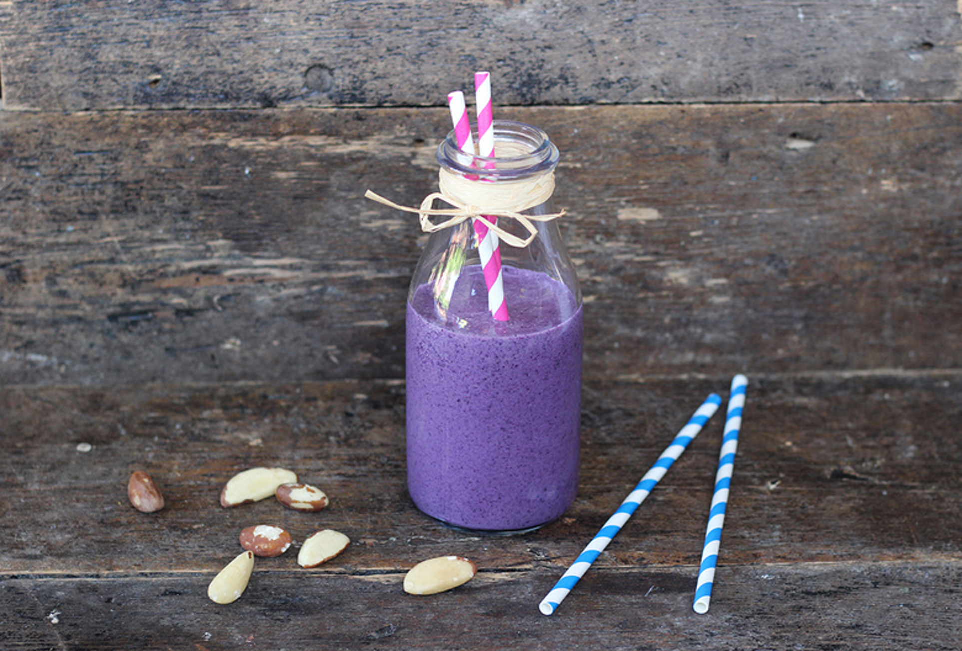 Vibrant smoothie with mixed berries, Brazil nuts, and a creamy swirl in a clear glass