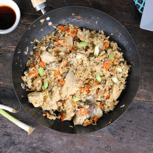 Classic fried rice with tender chicken pieces, scrambled egg, peas, and spring onions in a wok