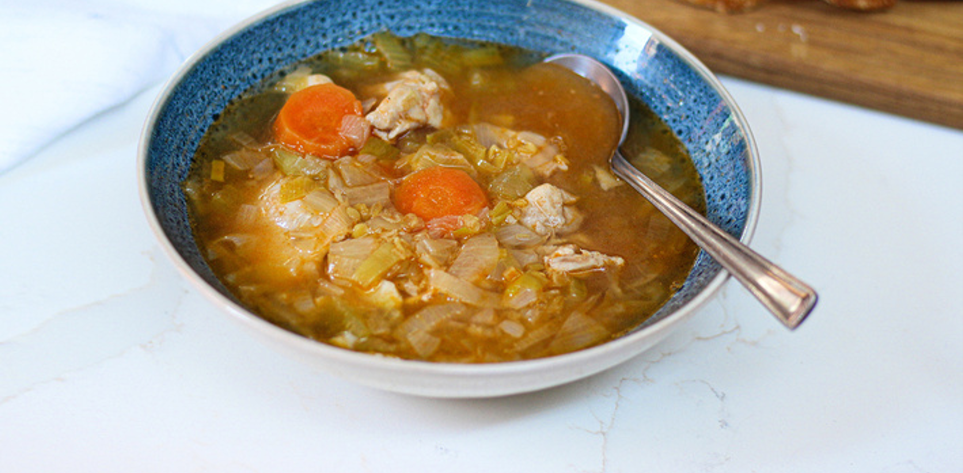 Creamy chicken and lentil soup with tender leeks, shredded chicken, and herbs in a comforting bowl