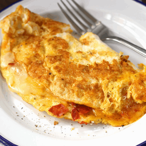 Golden omelette with spicy chorizo slices, melted cheese, and herbs on a ceramic plate