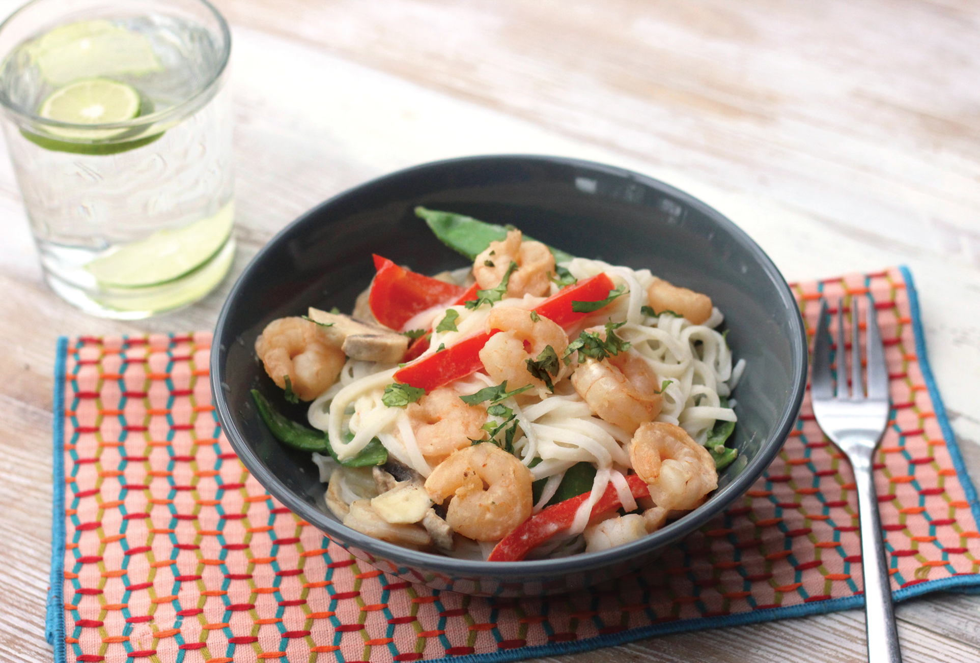 Stir fry with prawns, vegetables, and a coconut lemongrass sauce in a wok garnished with fresh herbs