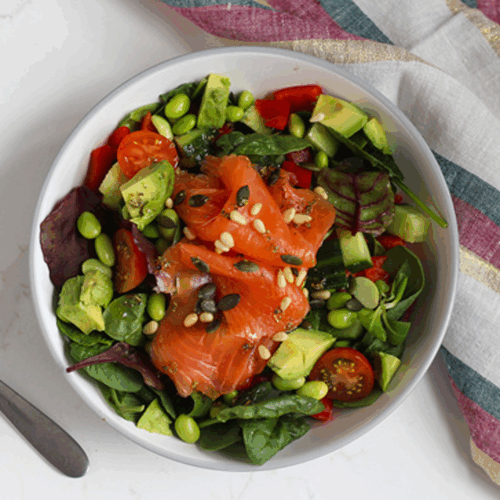 Crisp salad with flaked salmon, crunchy vegetables, and toasted seeds on a rustic plate