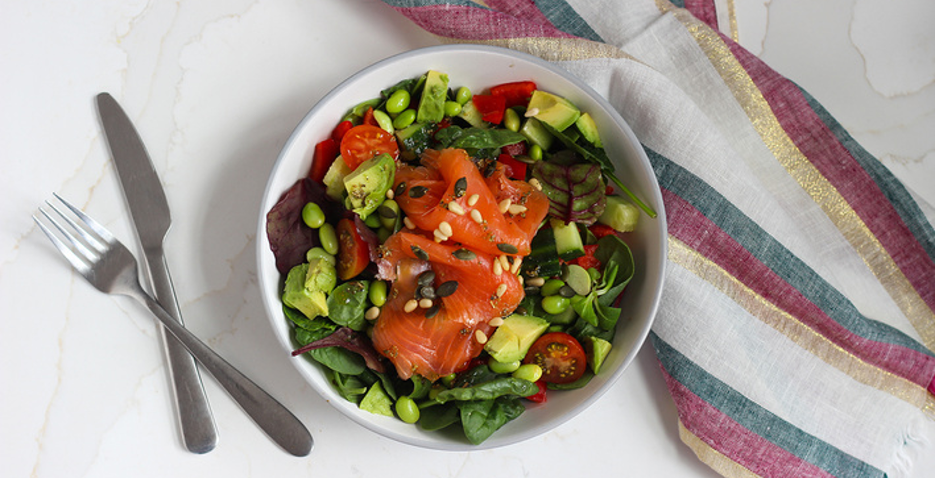 Crisp salad with flaked salmon, crunchy vegetables, and toasted seeds on a rustic plate