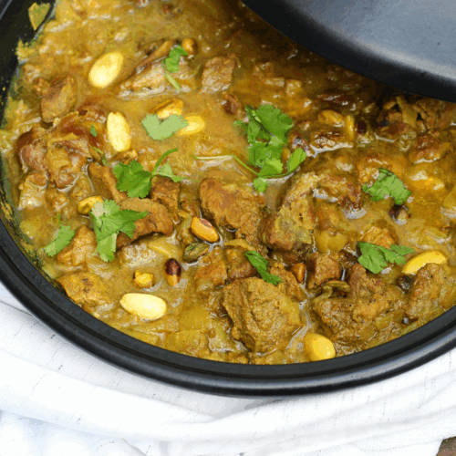 Moroccan lamb tagine with apricots, almonds, and herbs in a rustic ceramic dish served with couscous