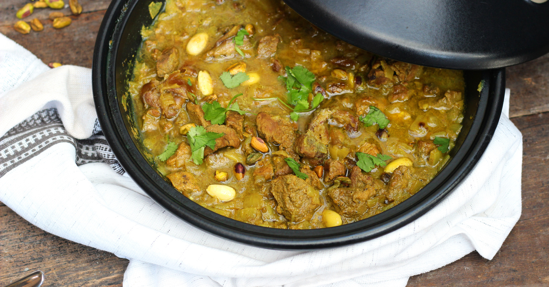 Moroccan lamb tagine with apricots, almonds, and herbs in a rustic ceramic dish served with couscous