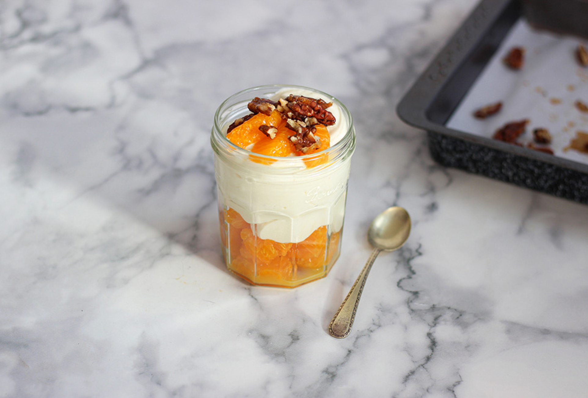 Bowl of creamy yogurt topped with mandarin segments, chia seeds, and a drizzle of honey on a light background