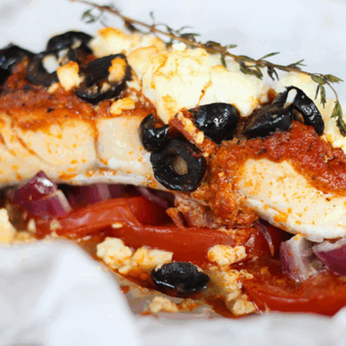 Baked white fish fillet topped with cherry tomatoes, black olives, herbs, and a drizzle of olive oil on a ceramic dish