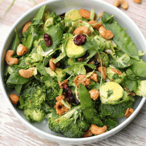 Bowl of shredded raw broccoli and Brussels sprouts with cashews, cranberries, and a light vinaigrette