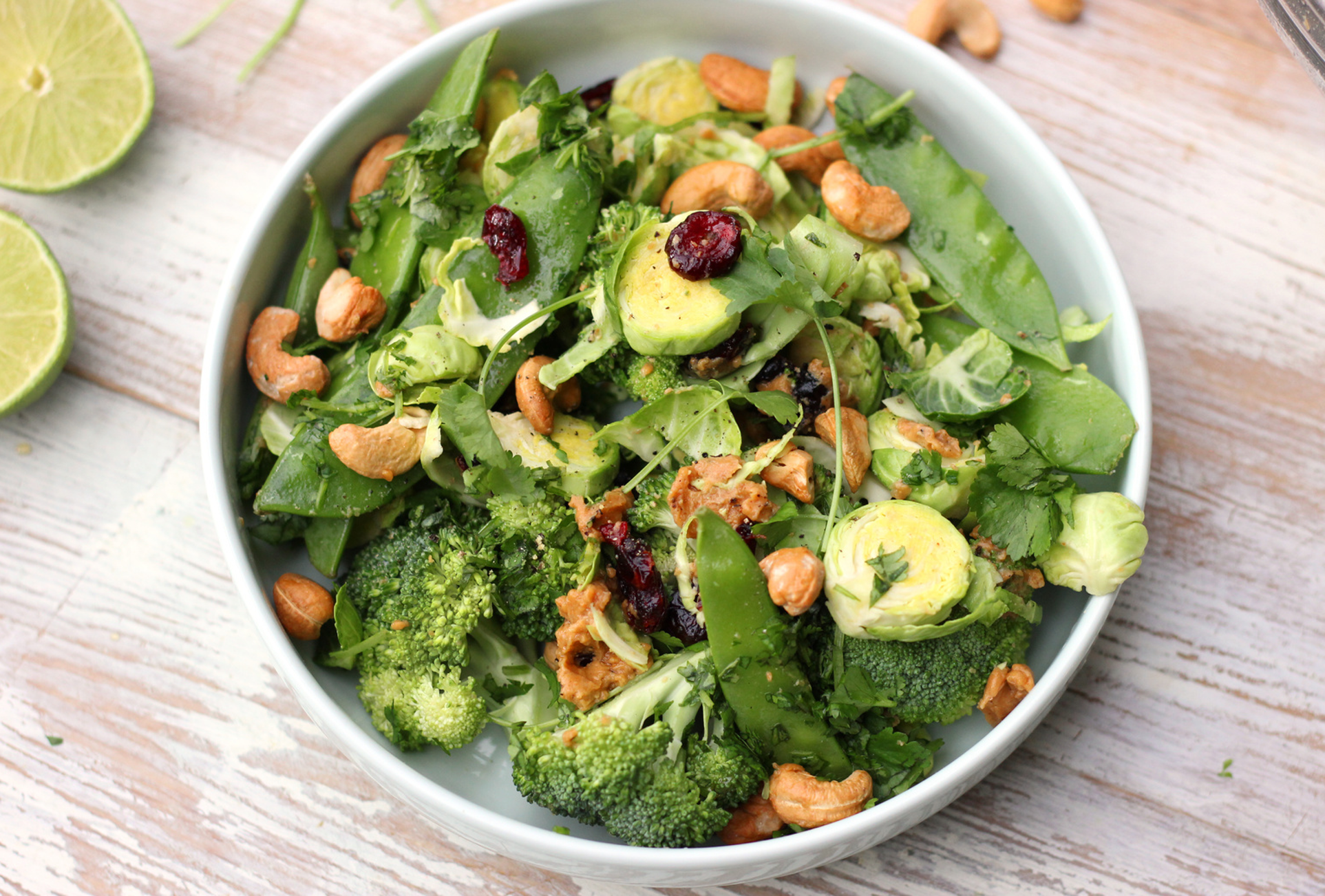 Bowl of shredded raw broccoli and Brussels sprouts with cashews, cranberries, and a light vinaigrette